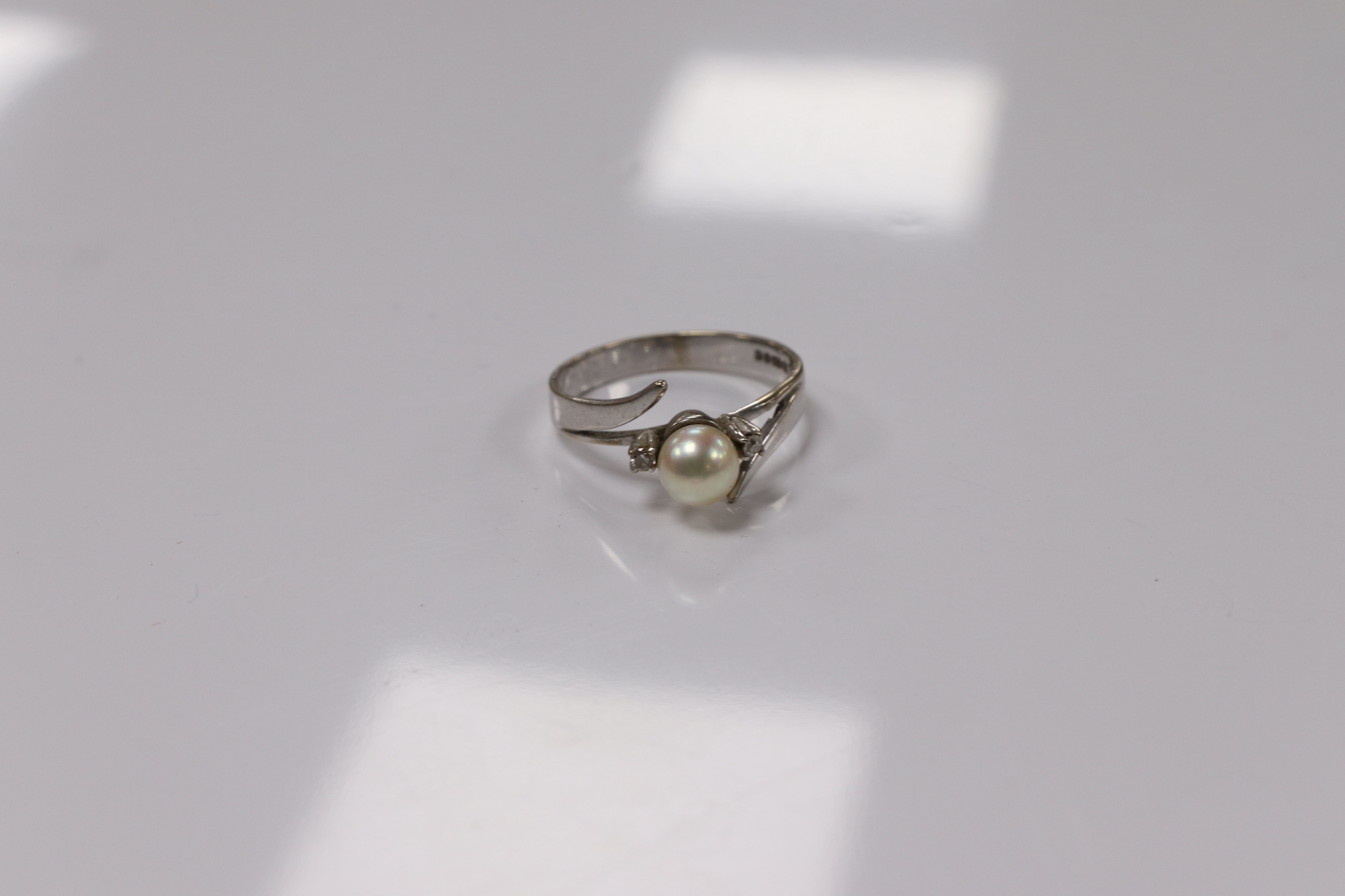 A modern 18ct white gold and single stone cultured pearl set ring, with two stone diamond set shoulders, size Q, gross weight 3.7 grams. Condition - poor to fair